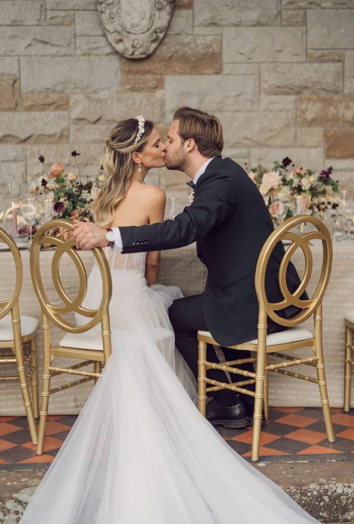Bride and groom sharing a kiss while seated at their wedding reception