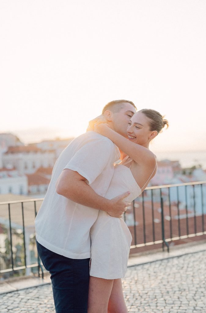 A couple embracing at sunrise during their engagement photoshoot in Alfama, Lisbon.